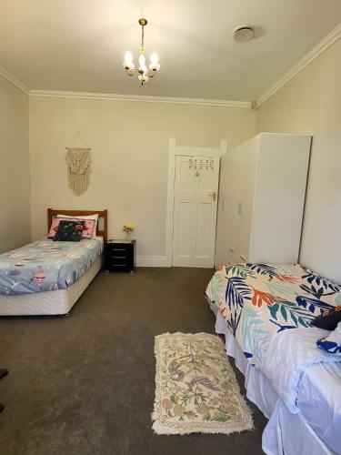 a bedroom with two beds and a chandelier at Gem on Bastia Hill in Whanganui