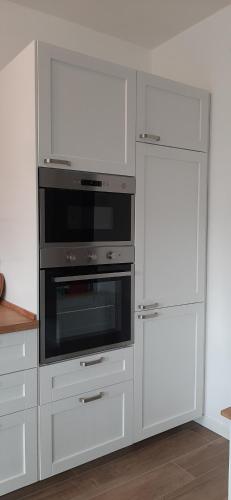 a kitchen with white cabinets and a microwave oven at Canaletto apartment con parcheggio in Dolo