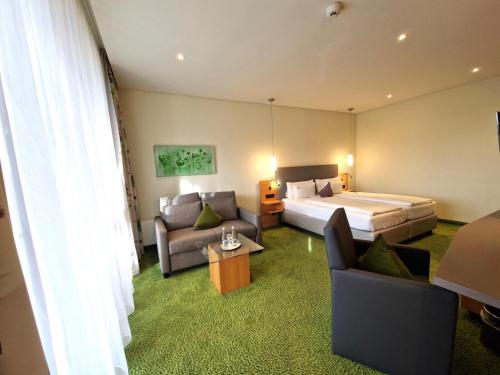 a hotel room with a bed and a couch and chairs at Mosers Blume Relax & Genuss Hotel in Haslach im Kinzigtal