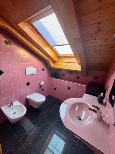 a pink bathroom with a sink and a toilet at Mansarda da Nonna Berbelina in Belluno