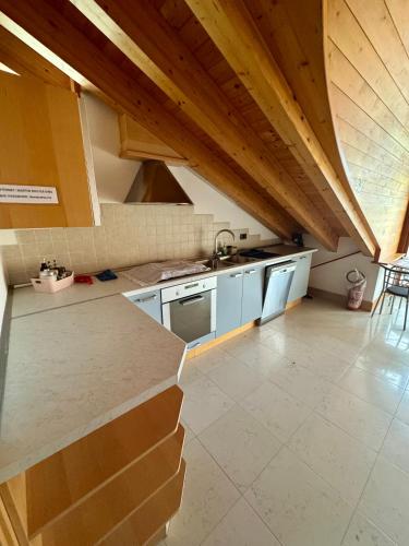 an attic kitchen with white appliances and wooden ceilings at Mansarda da Nonna Berbelina in Belluno