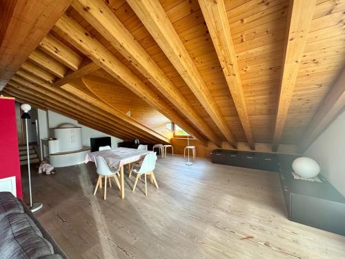 a living room with a table and chairs and wooden ceilings at Mansarda da Nonna Berbelina in Belluno