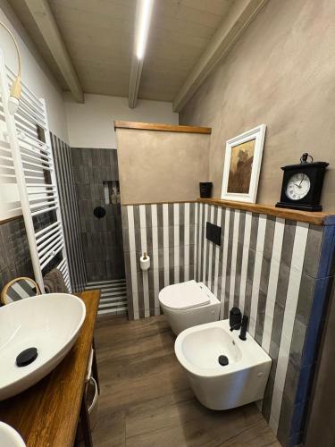 a bathroom with a sink and a toilet and a clock at B&B Villa la Canonica con piscina a Padernello in Farfengo