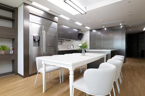 a kitchen with a white table and white chairs at Brown Suites Busan Station in Busan