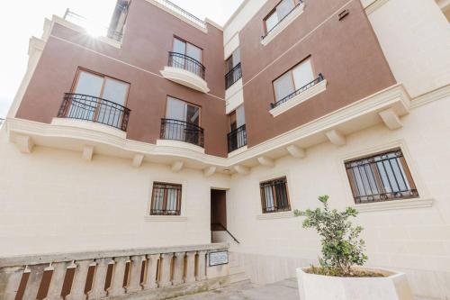 a building with balconies and a tree in a pot at 1bed Mel Apt W Church Views By Homely Malta! in Mellieħa