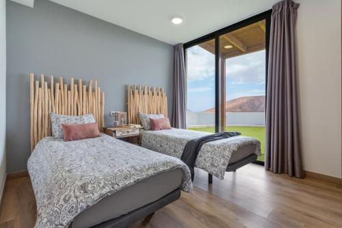Un dormitorio con dos camas y una gran ventana. en Volcanoa, en Villaverde
