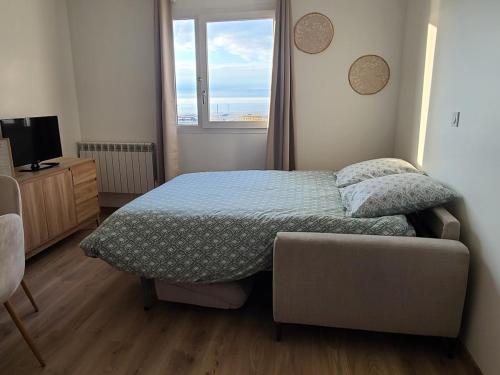 une chambre avec un lit, un canapé et une fenêtre dans l'établissement Appartement à la plage, vue sur la mer, à Calais