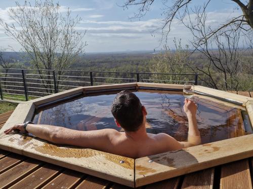a man in a hot tub with a glass of wine at La Vida Panorama in Batina