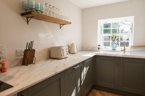 a kitchen with gray cabinets and a counter top at Rosebank Cottage - Hot Tub & Log Stove in Alexandria
