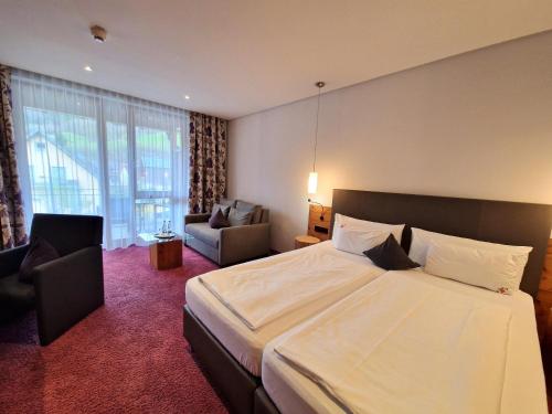 a hotel room with a large bed and a chair at Mosers Blume Relax & Genuss Hotel in Haslach im Kinzigtal