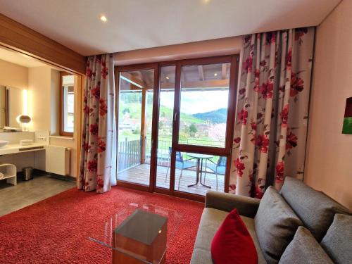 a living room with a couch and a large window at Mosers Blume Relax & Genuss Hotel in Haslach im Kinzigtal