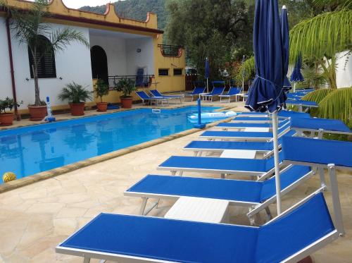a row of blue chairs and umbrellas in a swimming pool at Villafiorita in Gioiosa Marea
