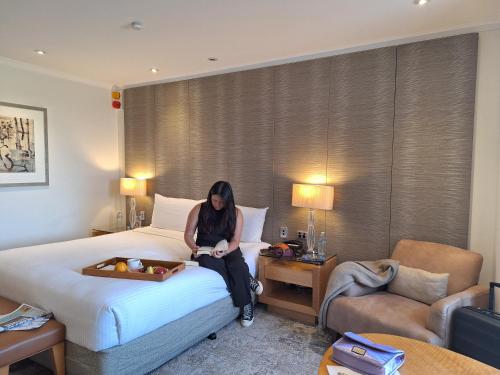 a woman sitting on a bed in a hotel room at Residence on Langley Park in Perth