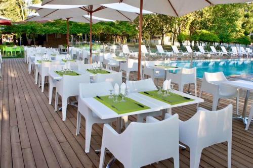 - une rangée de tables et de chaises blanches à côté de la piscine dans l'établissement Luxury Lodge, à Ghisonaccia