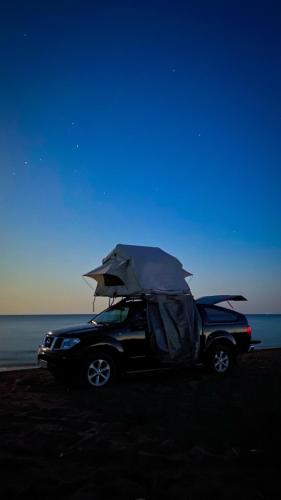 a car parked on the beach with an umbrella at car camping rental in Shkodër