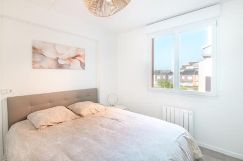 une chambre blanche avec un lit et une fenêtre dans l'établissement L’Écume de Courseulles - A 2min de la plage, à Courseulles-sur-Mer