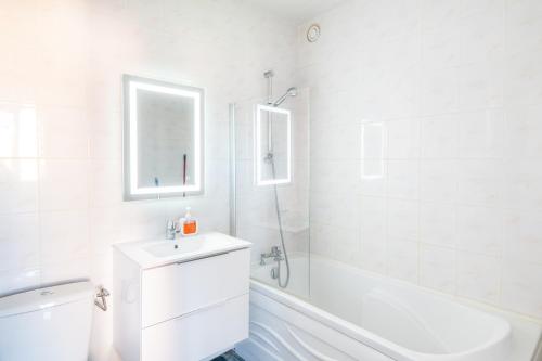 une salle de bain blanche avec un lavabo et une baignoire dans l'établissement L’Écume de Courseulles - A 2min de la plage, à Courseulles-sur-Mer