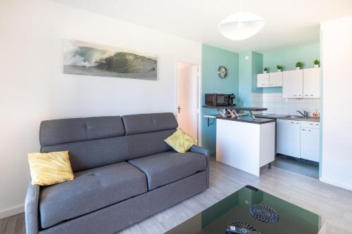 un salon avec un canapé et une cuisine dans l'établissement L’Écume de Courseulles - A 2min de la plage, à Courseulles-sur-Mer