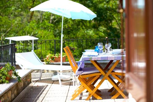 a table and chairs with a blue umbrella on a patio at Casa del Bosco - Vista mozzafiato & Parco 4 ettari in Bobbio