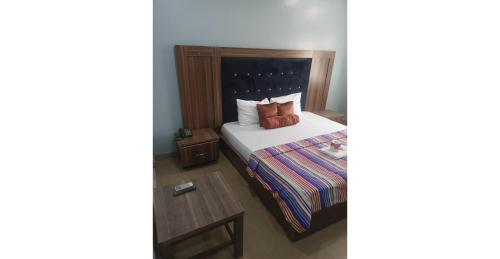 a bedroom with a bed with a pillow and a table at Angels Court Hotel and Suite in Kubwa