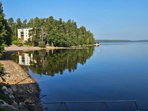 a view of a lake with trees and a building at Saimaa Gardens Apartment near Beach in Rauha