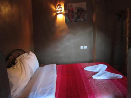 a bedroom with a bed with a red and white blanket at Kasbah Maison D’hôte Lalla Zahra in Aït Baha