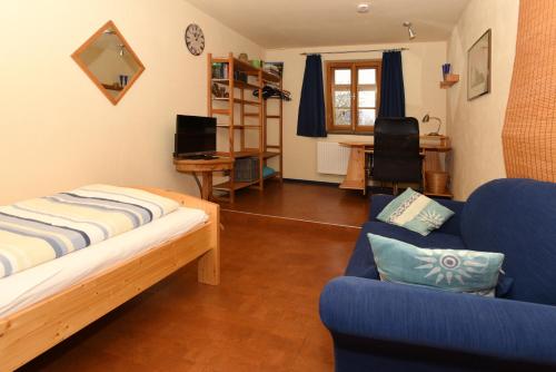 a living room with a blue couch and a desk at Ferienwohnung am Wasserschloss in Schnabelwaid