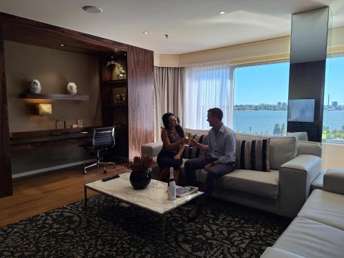 a man and woman sitting on a couch in a living room at Residence on Langley Park in Perth