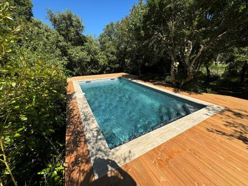 a swimming pool on a wooden deck with trees at Chemin de Ronze - Maison au calme avec piscine in Labastide-de-Virac