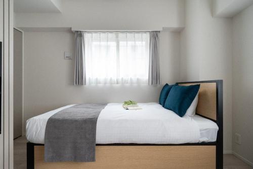 a bedroom with a bed with blue pillows and a window at Reve Asakusa in Tokyo