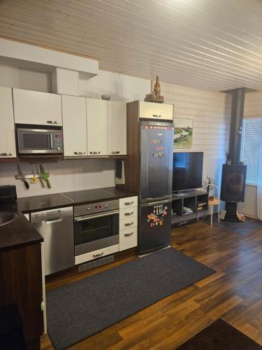 a kitchen with stainless steel appliances and a tv at Saimaa Gardens Apartment near Beach in Rauha
