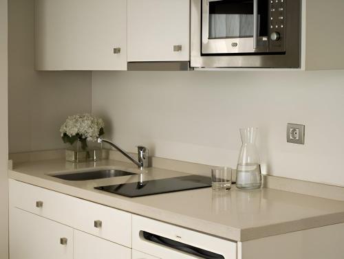 a kitchen with a sink and a microwave at Suites Viena Plaza de España in Madrid