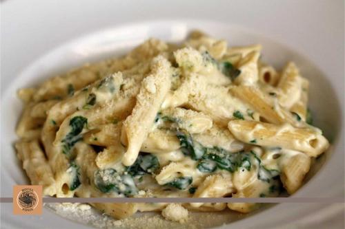 a plate of pasta with cheese and spinach at Hotel Főnix in Pécs