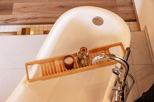 a bath tub with a wooden shelf next to a sink at Landhaus Trinis - Kleine Kaffee Tee Theke mit Kühlschrank - Parkplatz in Rottach-Egern