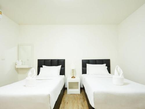 two beds in a room with white walls at Bansuay Phranangklao Apartment&Hotel in Ban Sai Ma