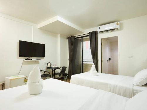 a hotel room with two beds and a flat screen tv at Bansuay Phranangklao Apartment&Hotel in Ban Sai Ma