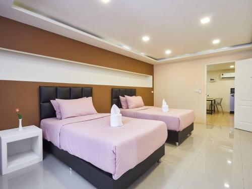 a bedroom with two beds with pink pillows at Bansuay Phranangklao Apartment&Hotel in Ban Sai Ma