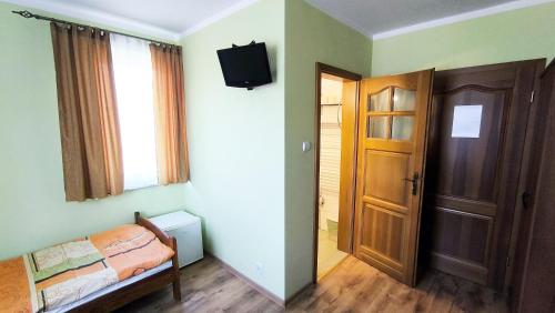 a bedroom with a bed and a door and a television at Jaś i Małgosia nad Jeziorem Wigry in Rosochaty Róg