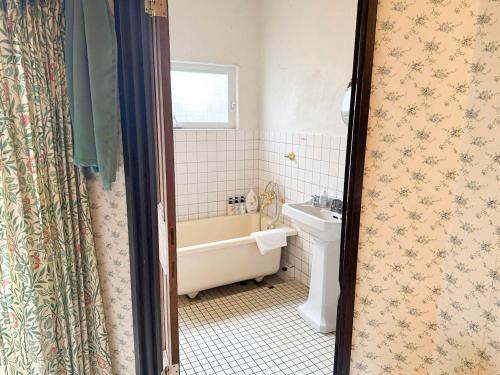 a bathroom with a tub and a sink at Gasthof Ami in Nikko