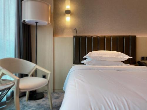 a bedroom with a bed and a chair and a lamp at Chongqing Liyuan Hotel in Chongqing