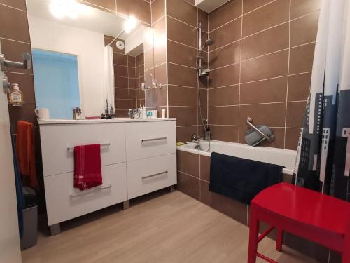 La salle de bains est pourvue d'une coiffeuse blanche, d'une baignoire et d'un lavabo. dans l'établissement Appartement cosy à Valras-Plage 5 min à pied de la mer Climatisé 2 chambres Terrasse, à Sérignan