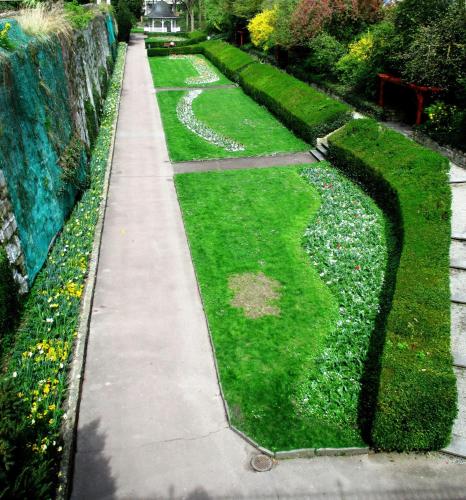 a garden with green grass and a sidewalk at Hotel am Stadtgarten in Radolfzell am Bodensee