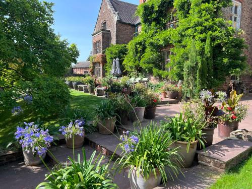 a garden with lots of potted plants in front of a building at Uplands Guest House in Ledbury