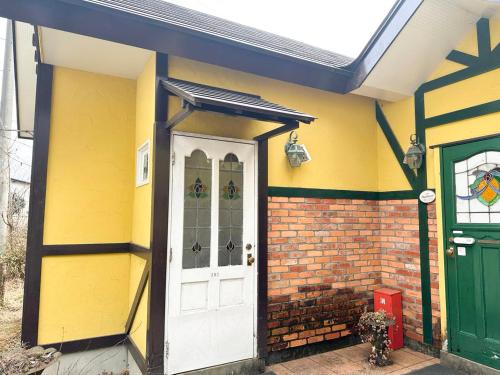 a yellow house with a white door and a green door at Gasthof Ami in Nikko