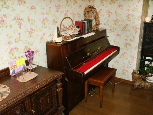 an old piano in a room with a table and a desk at Gasthof Ami in Nikko