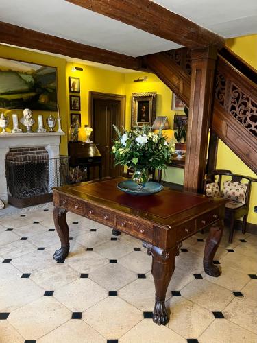 a room with a table with a vase of flowers on it at Uplands Guest House in Ledbury