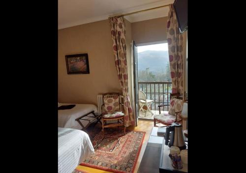 a bedroom with a bed and a window with a balcony at Logis Hôtel Beau Site in Argelès-Gazost