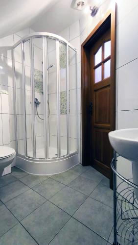 a bathroom with a shower and a toilet and a door at Jaś i Małgosia nad Jeziorem Wigry in Rosochaty Róg