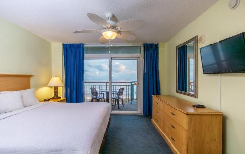 een slaapkamer met een bed, een televisie en een balkon bij Paradise Resort in Myrtle Beach