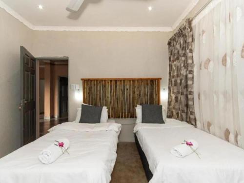 two beds in a room with white sheets and flowers on them at Woodpecker's Guest House in Hazyview